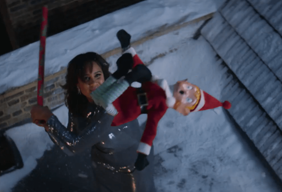 Zawe Ashton is seen launching an Elf on the Shelf toy from a roof