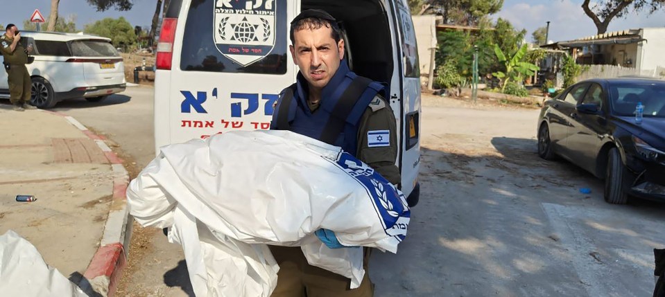 An Israeli rescuer carries what appears to be a child after the Kibbutz Be'eri massacre