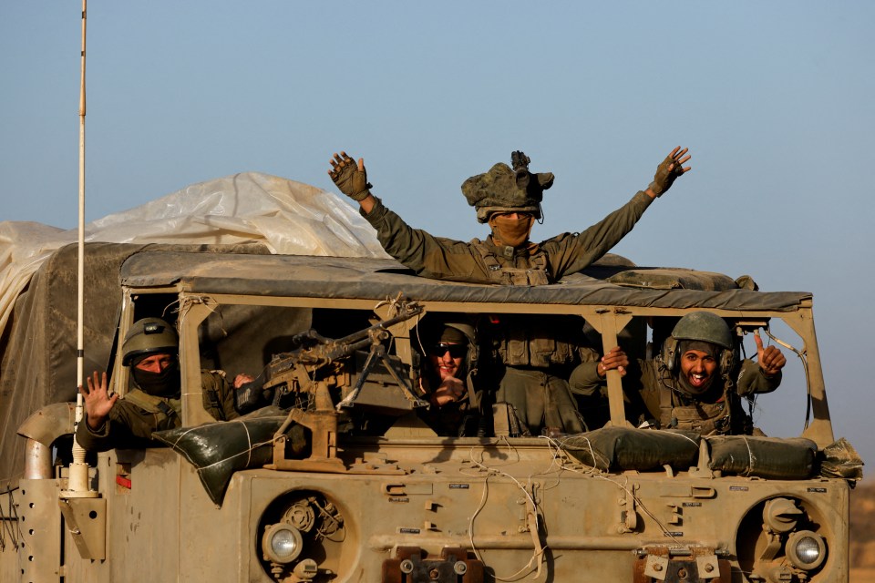 Israeli soldiers pose for the camera as they leave Gaza during the temporary truce