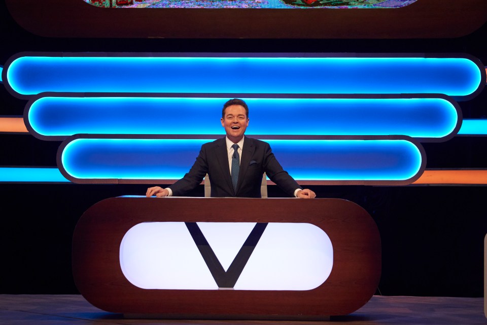 a man stands behind a desk with the letter v on it