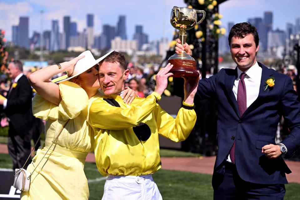 Zahra celebrates with a kiss from wife Elyse as co-trainer Freedman touches the trophy