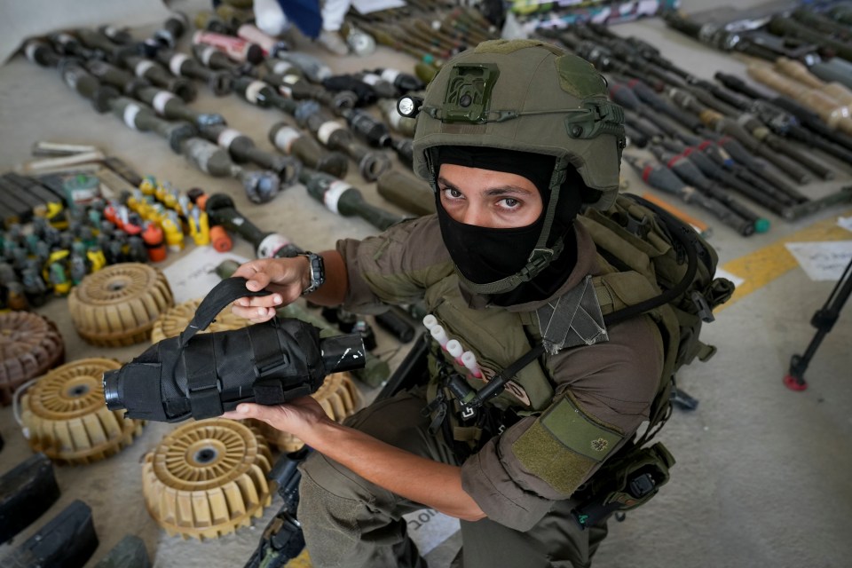 Major G shows off a thermobaric grenade in front of a cache of Hamas weapons supplied by Iran