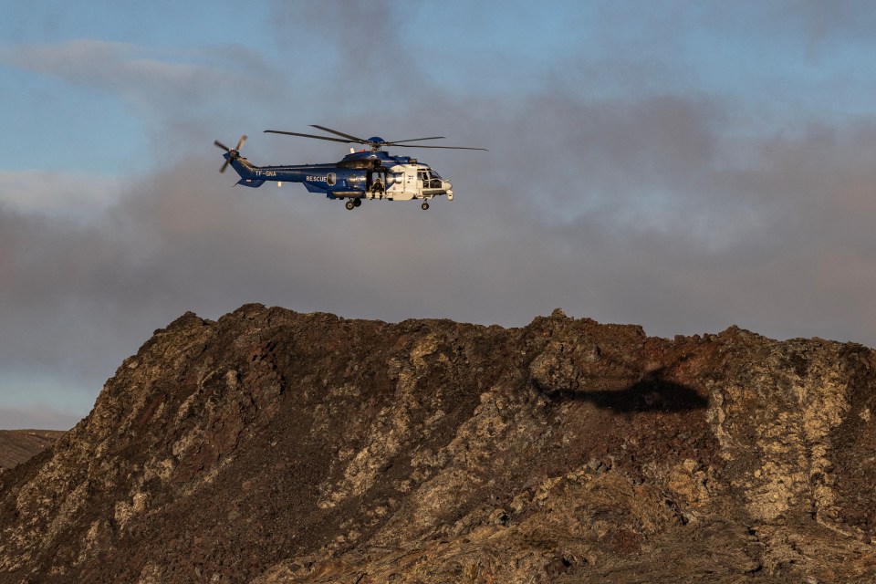 Members of the Coast Guard fly in a helicopter near Grindavik