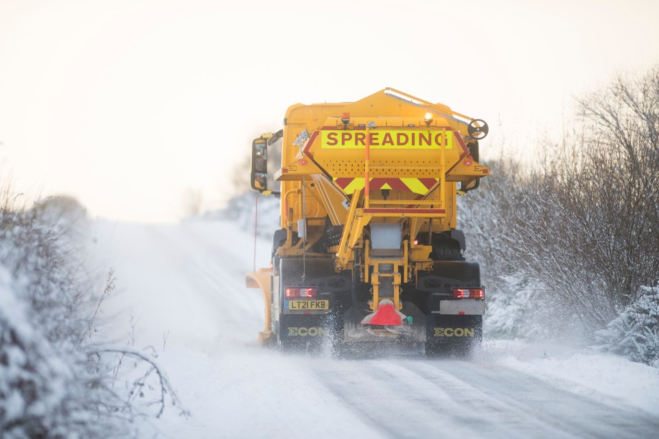 A snow plough drives a passage through the snow and grits the road in snowy North Yorkshire