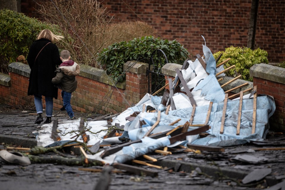 A woman and child step over debris in the aftermath