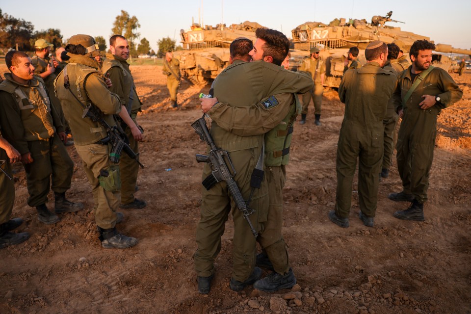 Soldiers embrace near tanks deployed on Israel's southern border with the Gaza Strip on Wednesday as the truce deal entered its sixth day