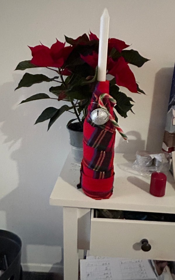 Discarded wine bottles get a glow up with a candle stick and a candy cane