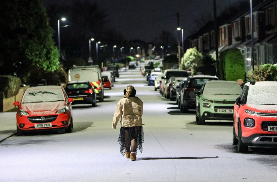 A woman walking down a snow covered road in the coastal village of Cullercoats in North Tyneside