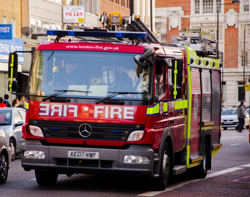 London, United Kingdom - February 19, 2012: Two firefighters appear inside a truck, which passes by a street of the city centre of the british capital city.