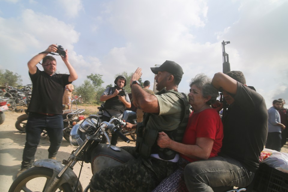 Palestinians transport a captured Israeli civilian, center, from Kfar Azza kibbutz into the Gaza Strip on Saturday, Oct. 7, 2023. The militant Hamas rulers of the Gaza Strip carried out an unprecedented, multi-front attack on Israel at daybreak Saturday, firing thousands of rockets as dozens of Hamas fighters infiltrated the heavily fortified border in several locations by air, land, and sea and catching the country off-guard on a major holiday. (AP Photo/Hatem Ali)