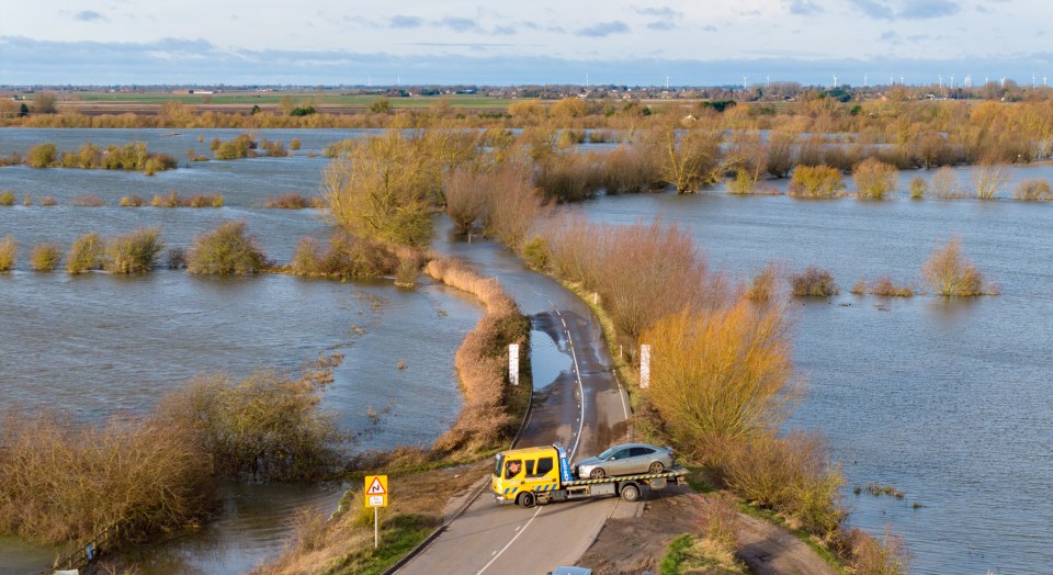 A car is towed away after getting stuck in floods on the A1101 in Norfolk yesterday