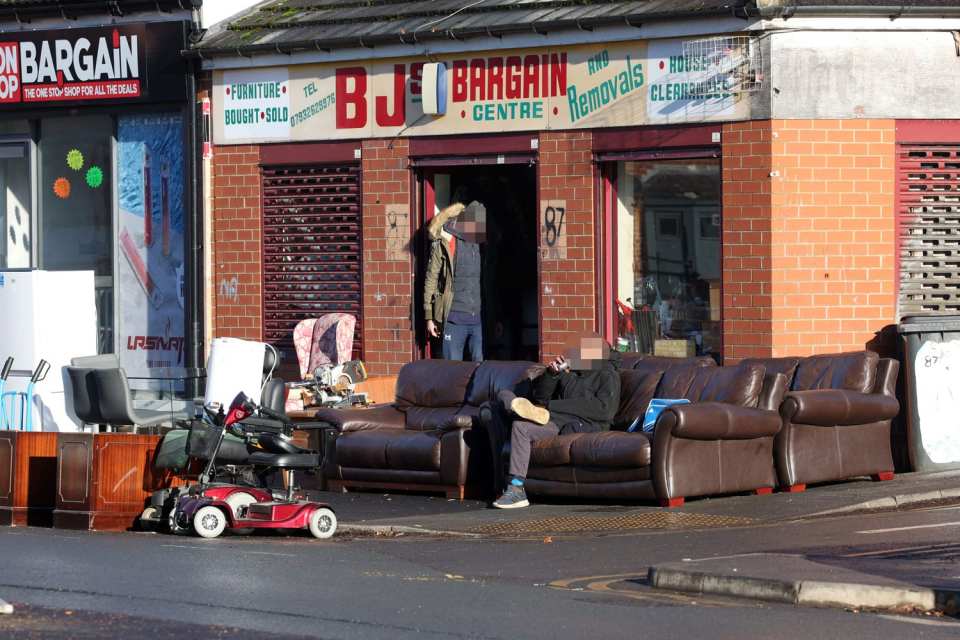 Alcoholics sit and sup beer on sofas for sale outside a furniture store