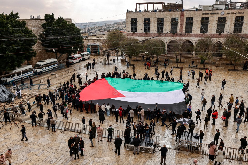 A giant Palestinian flag is somberly unfurled in Manger Square outside the Church of the Nativity - usually filled with decorations and festive celebrations