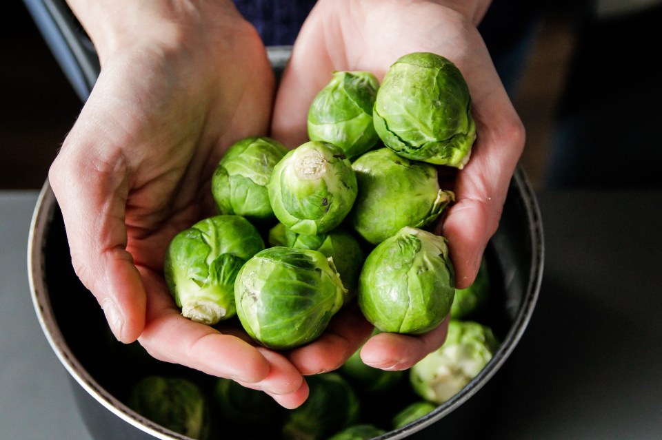 Hands holding a handful of Brussels sprouts.