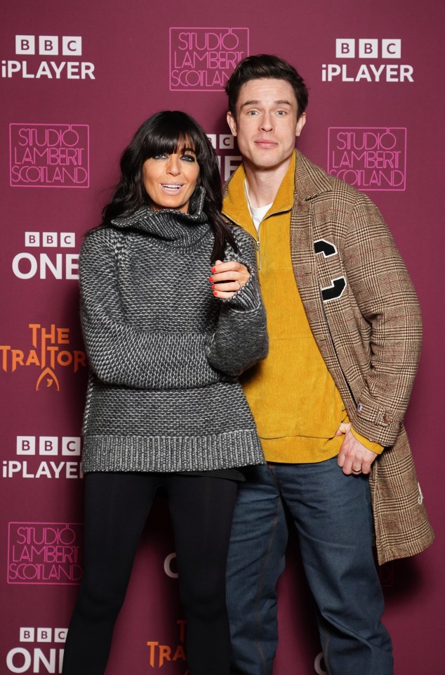 a man and a woman pose for a photo in front of a studio lambert scotland sign