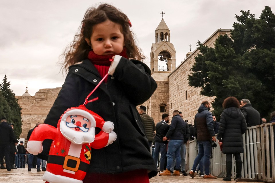 A girl stands with an inflatable Father Christmas doll at the Manger Square outside the Church of the Nativity