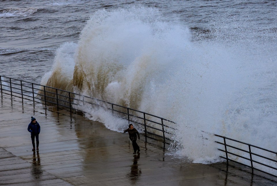 Walkers struggling in the heavy wind and rain on Whitley Bay promenade