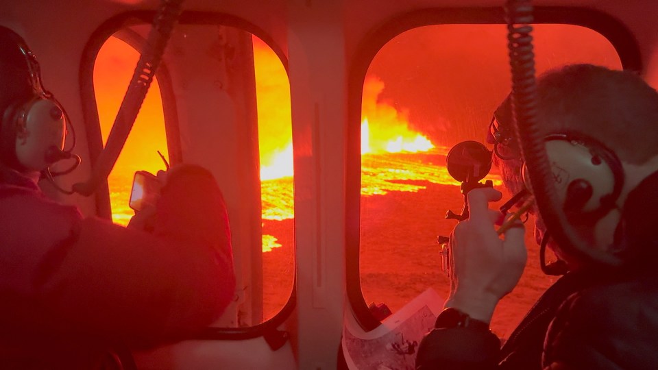 Emergency workers and scientists in an Icelandic Coast Guard helicopter flying over the eruption