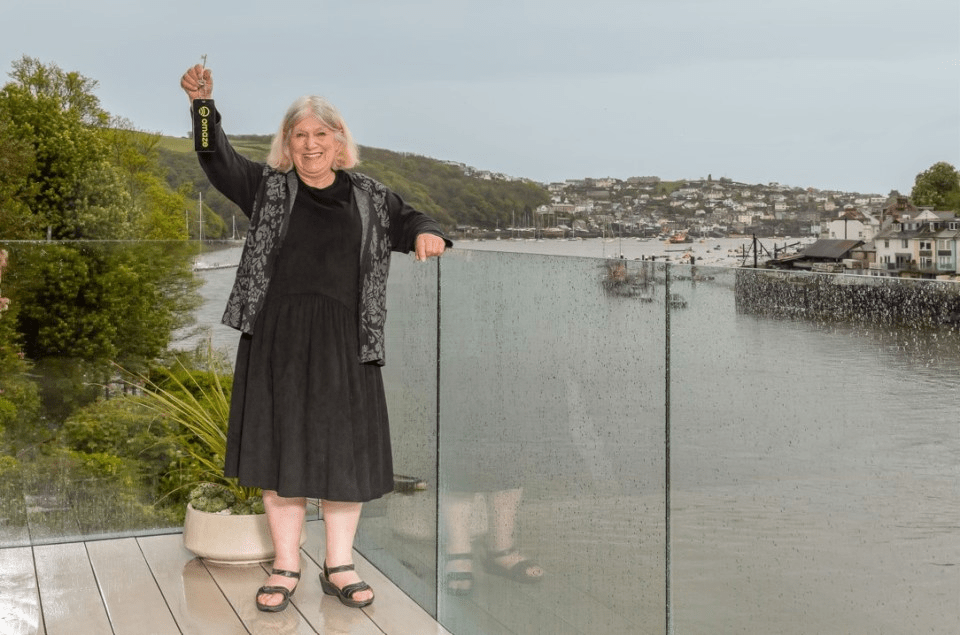 a woman stands on a balcony holding a bottle of champagne