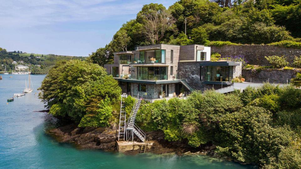 a house sits on a hill overlooking a body of water