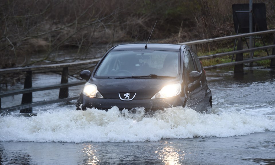 A motorist drives through floodwater on the outskirts of Billericay in Essex