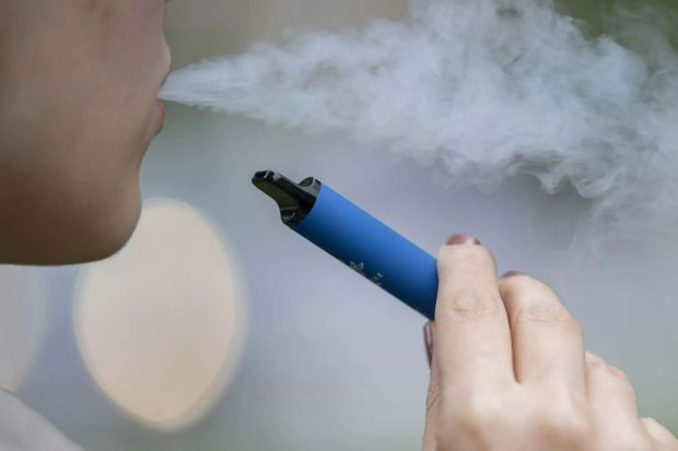 a person is blowing smoke out of a blue device