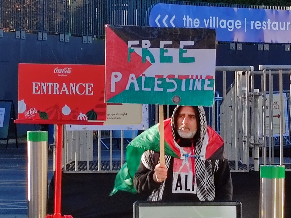 A protester named Ali stood at the entrance and held up different pro-Palestine signs