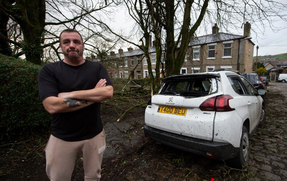 Andy Turner stood next to his wife's car which has been completely ruined after a tree fell onto it