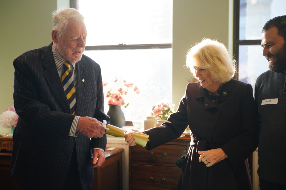 Queen Camilla and Sir Terry Waite pulled a cracker for a homeless charity Emmaus Bristol’s 25th anniversary