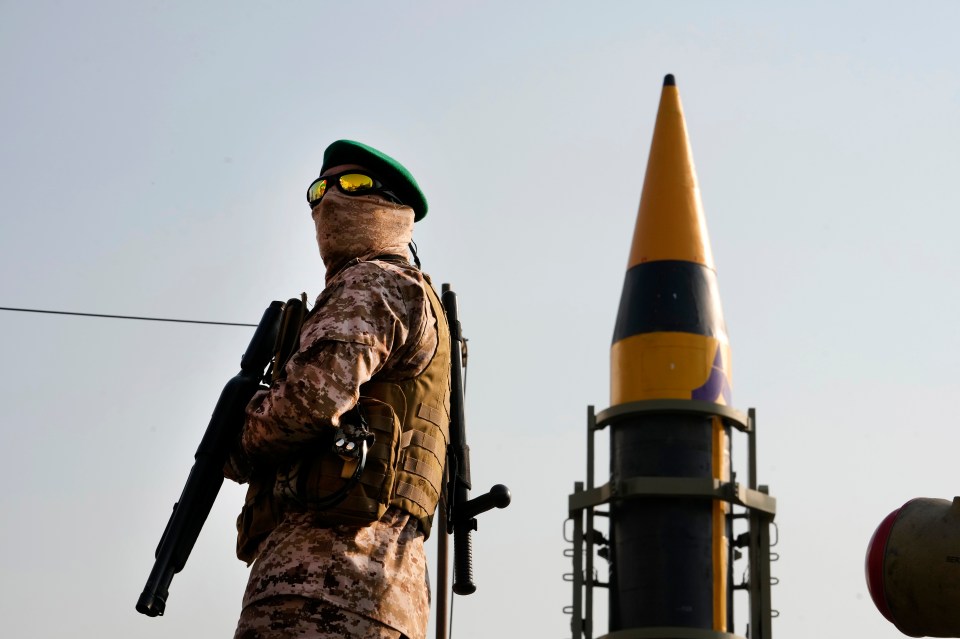 An Iranian Revolutionary Guardsman stands next to a missile. There are reports Iran is now close to completing a nuclear device.