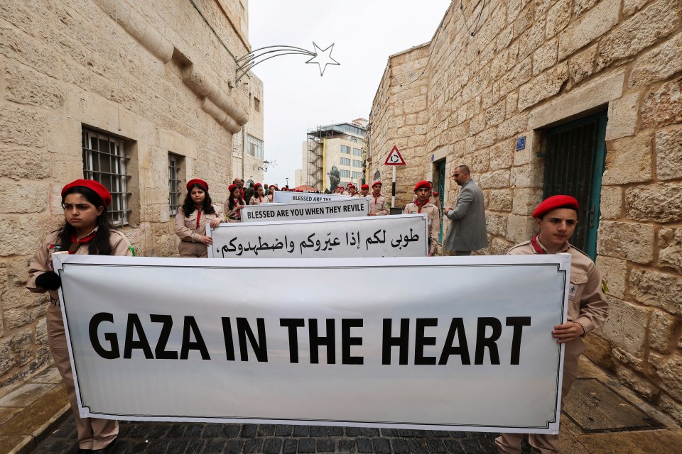 Young scouts quietly march through Bethlehem with signs about the ongoing war in Gaza