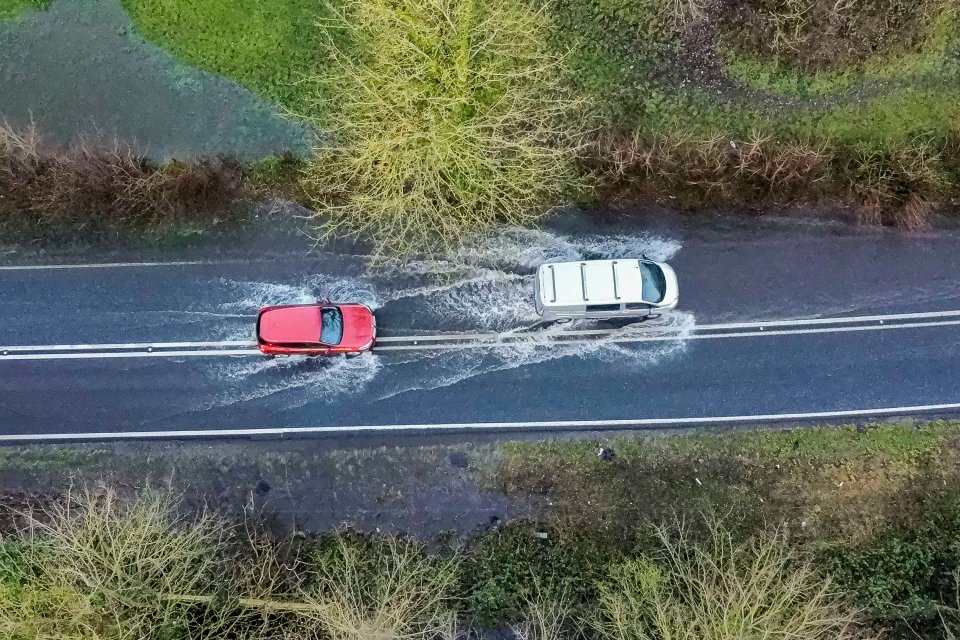 Vehicles drive through floodwater on the A35 near Winterbourne Abbas in Dorset, on Sunday