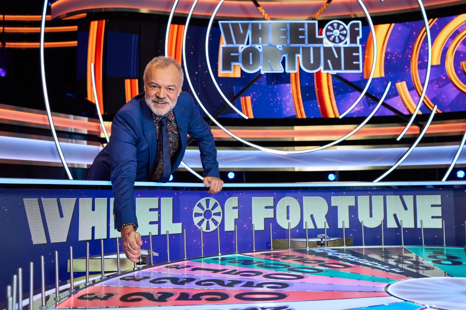 A man spinning the Wheel of Fortune.