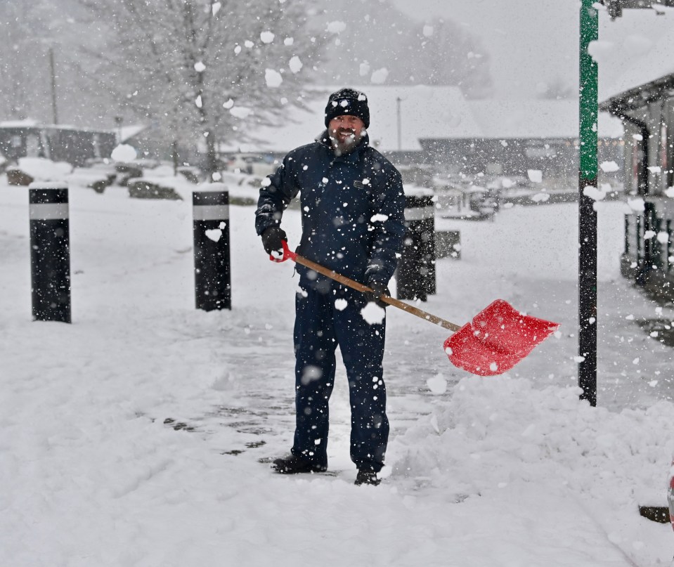 A man tries to clear the path in Bowness on Windermere in the Lake District yesterday morning