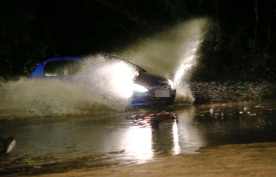 Motorists braving the floodwater in Godalming in Surrey yesterday