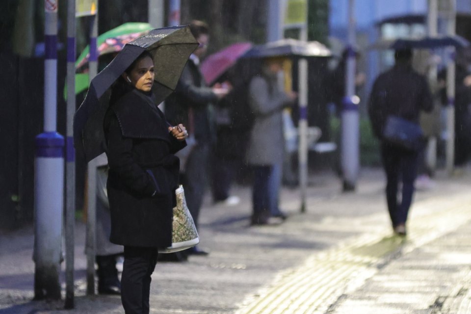 Commuters attempt to shelter during wet weather at Maze Hill Station in Greenwich, London