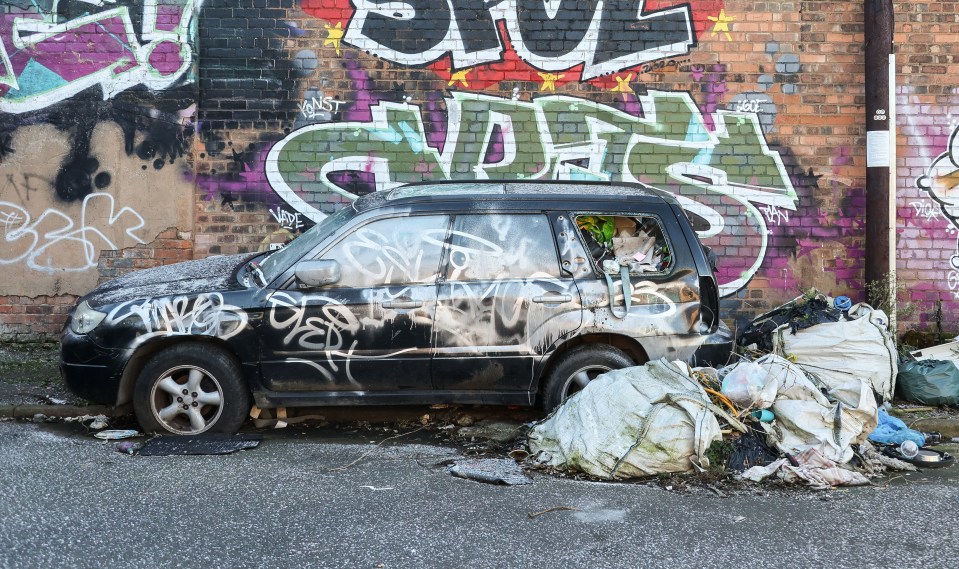 A derelict car stuffed full of rubbish has been left by the side of the road