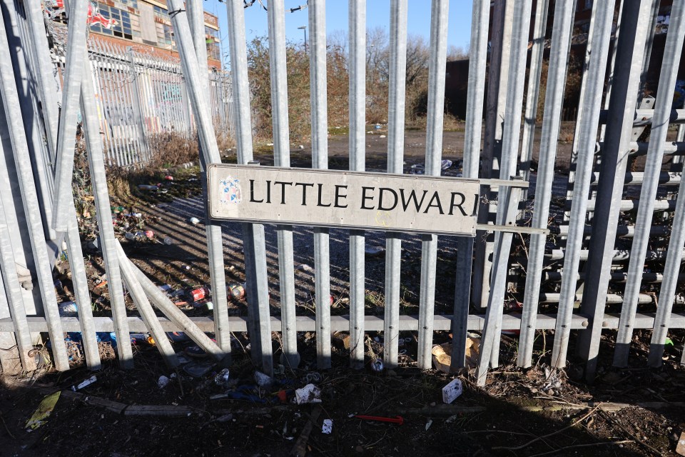 A broken street sign hangs off a smashed-in fence in Digbeth, Birmingham