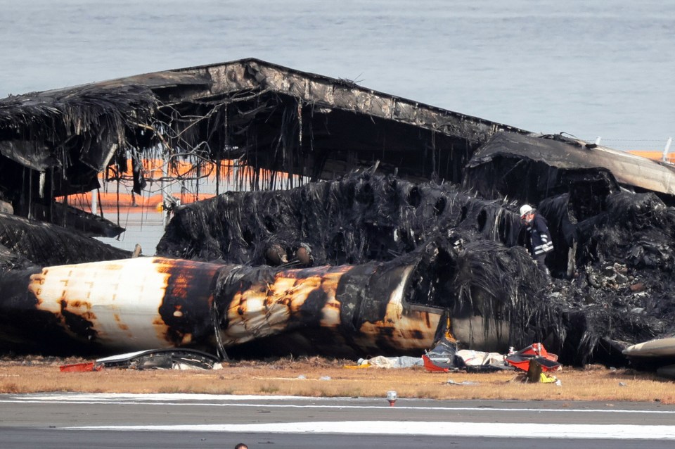 A firefighter investigates the debris of the Airbus A350 at Haneda Airport