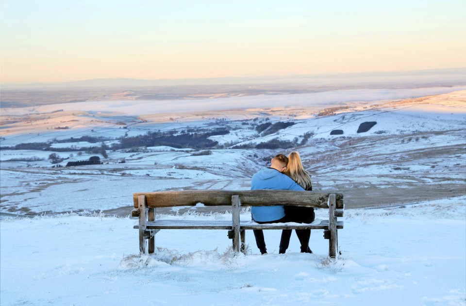 A young couple snuggle up on a bench at the Hartside Cafe in Alston, Cumbria