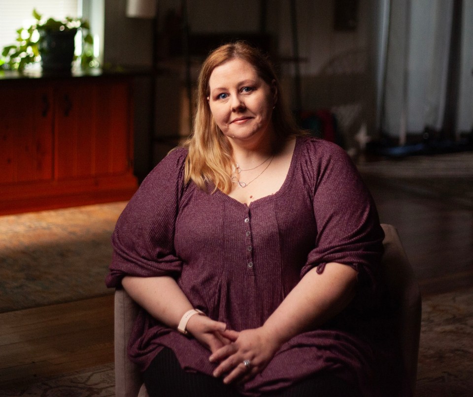 a woman in a purple shirt sits in a chair