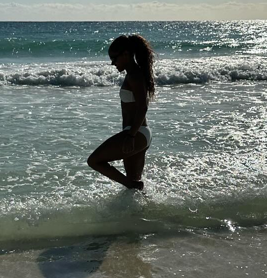 a woman in a bikini is standing in the ocean