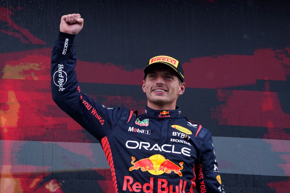 a man wearing a red bull shirt holds his fist in the air