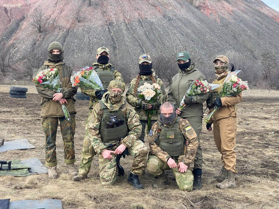 Football hooligan fighters from Russia's Española private military company offer flowers to their newly recruited women snipers at a military training base