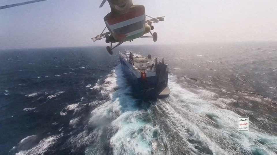 A Houthi military helicopter flies over the Galaxy Leader cargo ship in the Red Sea