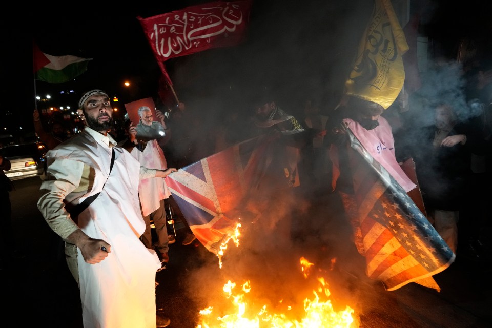 Protesters burn flags outside the British embassy in Tehran, Iran