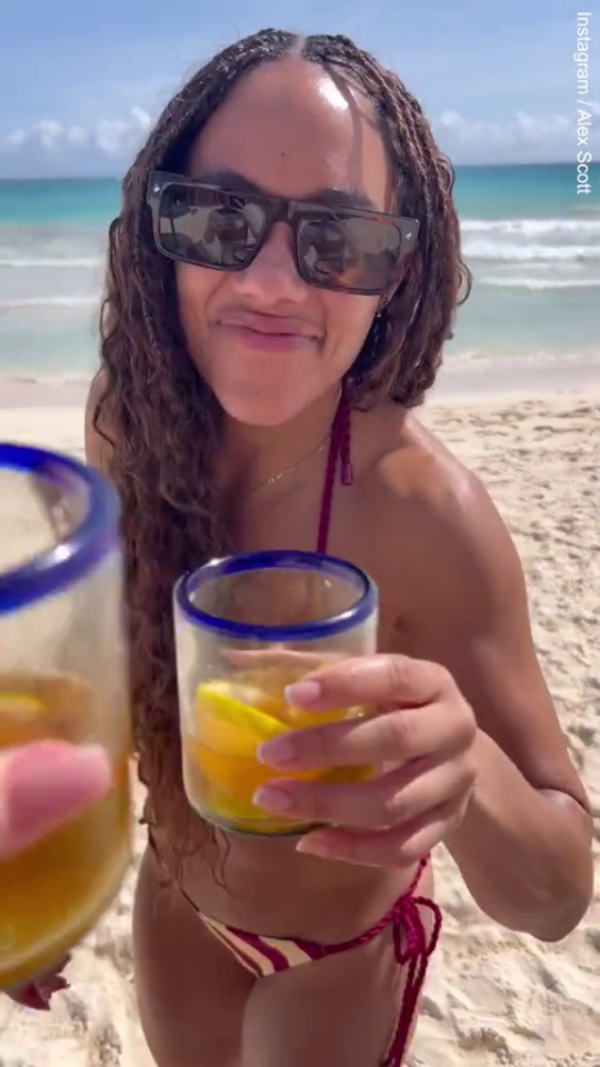 a woman in a bikini is holding two drinks on the beach .