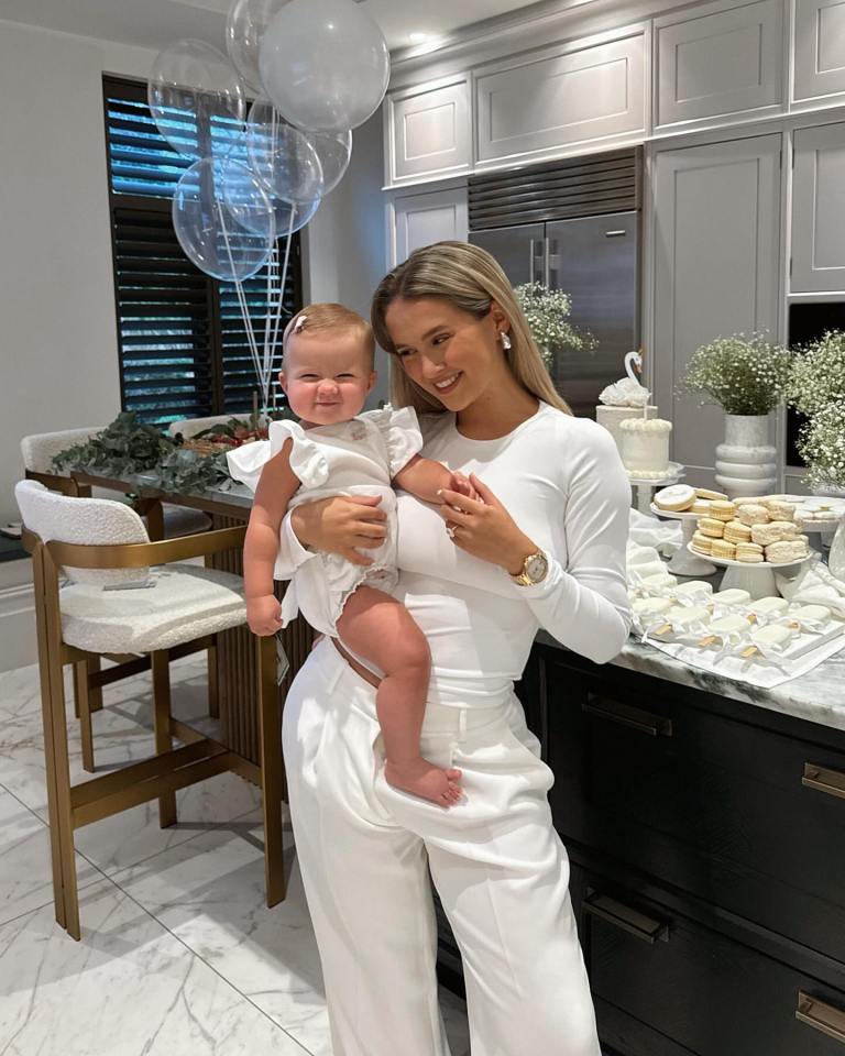 a woman holding a baby in a kitchen with balloons in the background