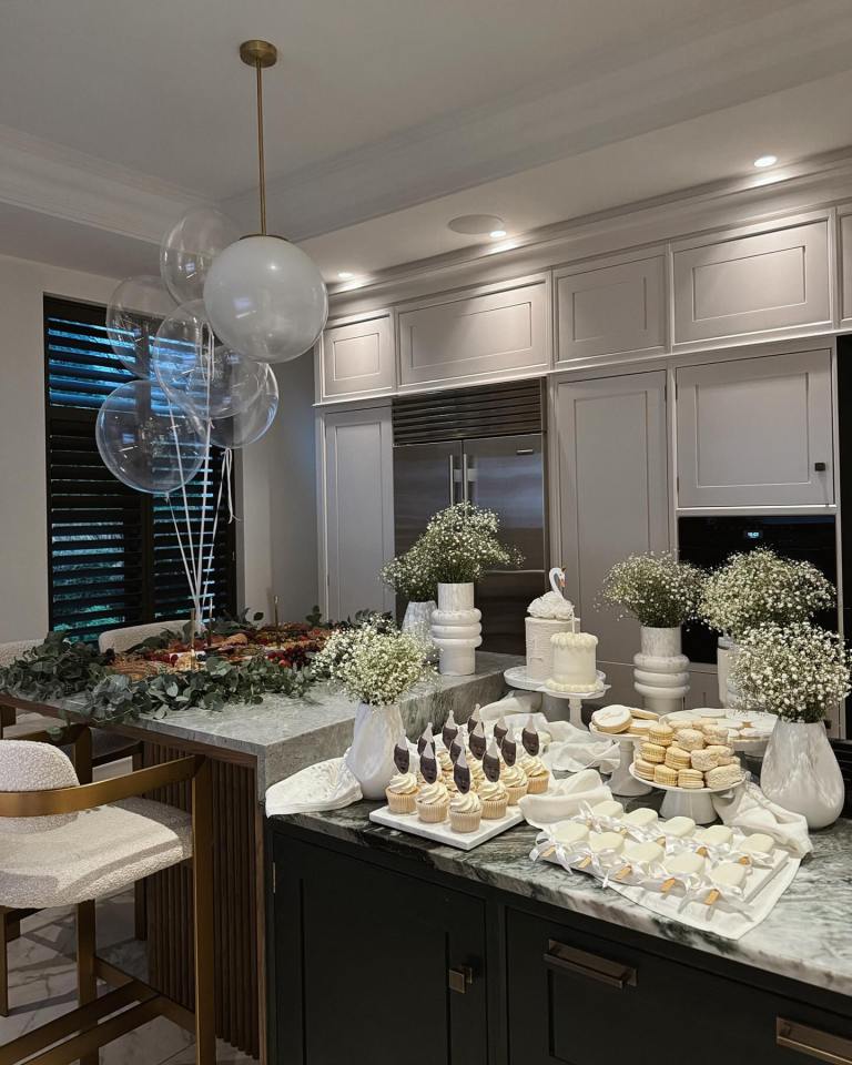 a kitchen with a table full of cupcakes and balloons