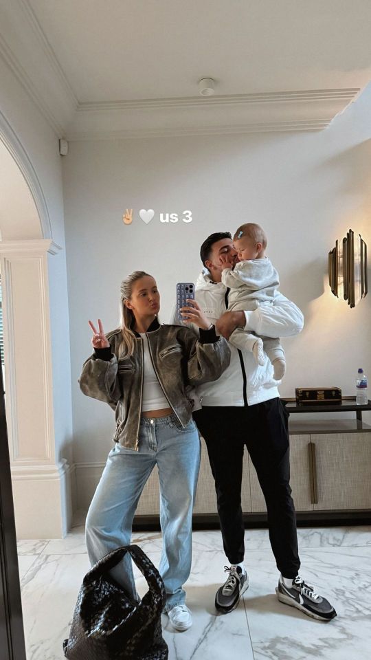 a man and woman holding a baby in front of a wall that says us 3